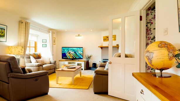 A living room with a sofa, armchair, coffee table, TV, and a globe on a wooden side table.