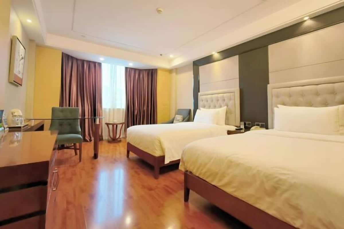 Une chambre d’hôtel avec deux lits, un bureau, une chaise et une petite table.