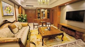 A living room with a sofa, coffee table, TV, and wooden cabinets. - Huaxia Hotel (Dazhou)