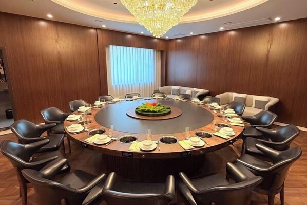 A conference room with a round table, black chairs, and a chandelier. - Huaxia Hotel (Dazhou)