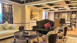 A modern living room with a sofa, armchairs, a round coffee table, and a dining area with chairs and a table. - Huaxia Hotel (Dazhou)