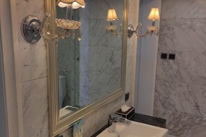 A bathroom with a large mirror, marble walls, and wall-mounted lighting fixtures. - Huaxia Hotel (Dazhou)