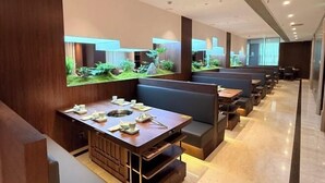A modern restaurant with wooden booths, a central dining table with tea sets, and a large aquarium wall. - Huaxia Hotel (Dazhou)