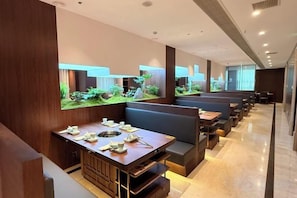 Un restaurante con cabinas y mesas, un acuario grande y una decoración de diseño moderno.