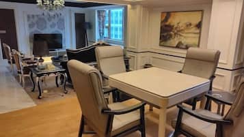 A dining area with a rectangular table and four chairs, a chandelier, and a painting on the wall.