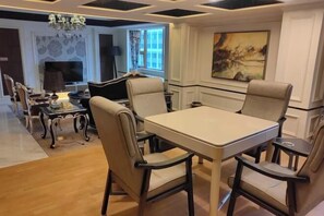 A dining area with a rectangular table and four chairs, a chandelier, and a painting on the wall. - Huaxia Hotel (Dazhou)
