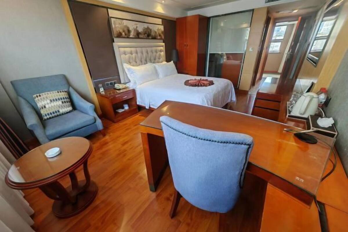Une chambre d’hôtel comprenant un lit, un bureau, une chaise, une petite table et une table de chevet.