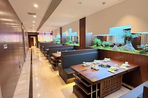 A restaurant with booths and a long counter, both with tables set for dining.