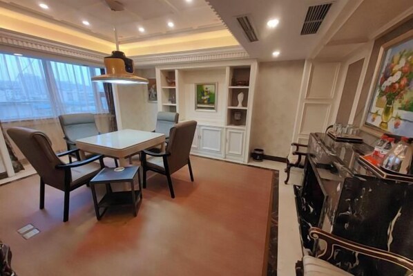 A dining area with a table and chairs, a chandelier, and a decorative cabinet with shelves. - Huaxia Hotel (Dazhou)