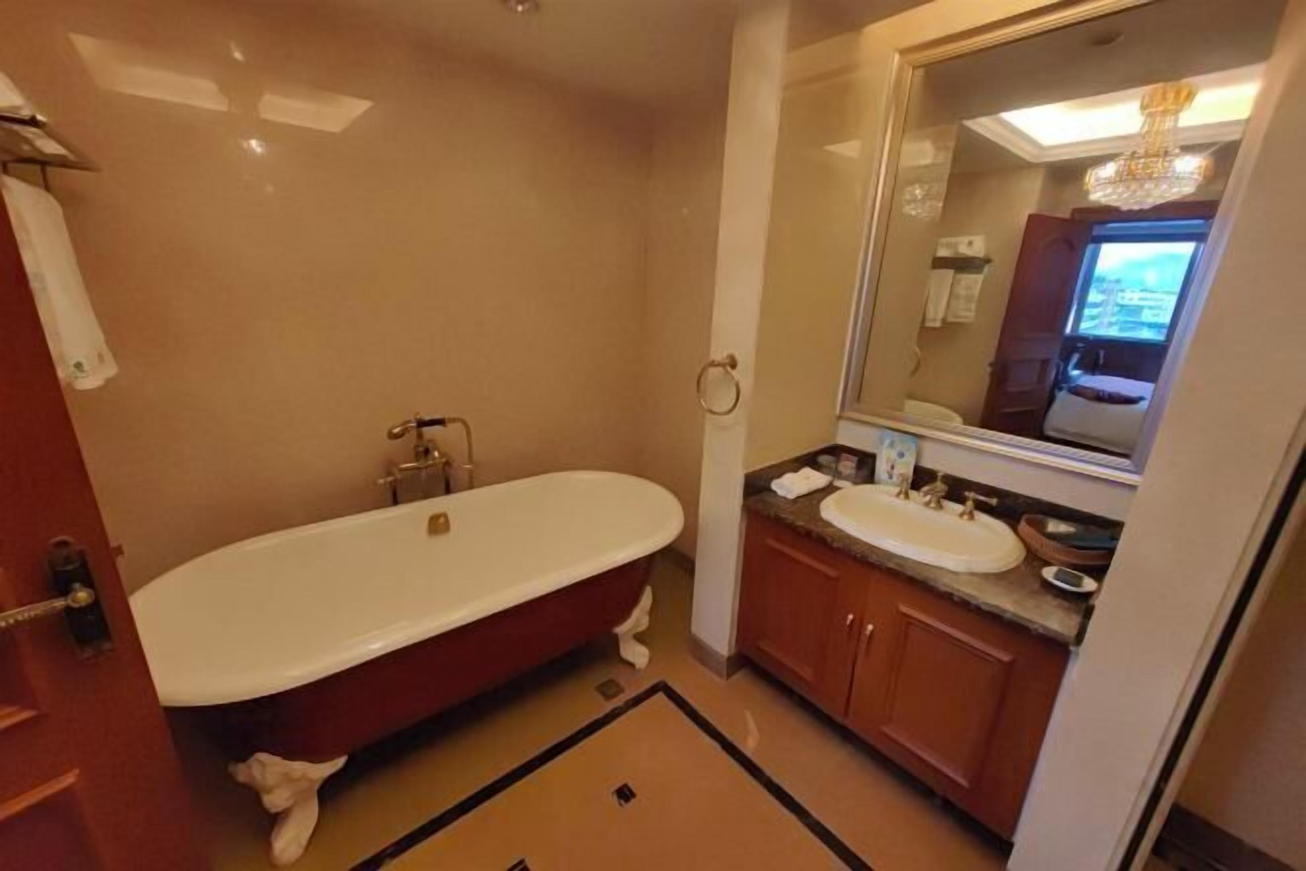 A bathroom with a large bathtub, a sink, and a mirror.