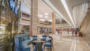 Un hall d’entrée spacieux avec un canapé bleu, des tables rondes et des chaises.