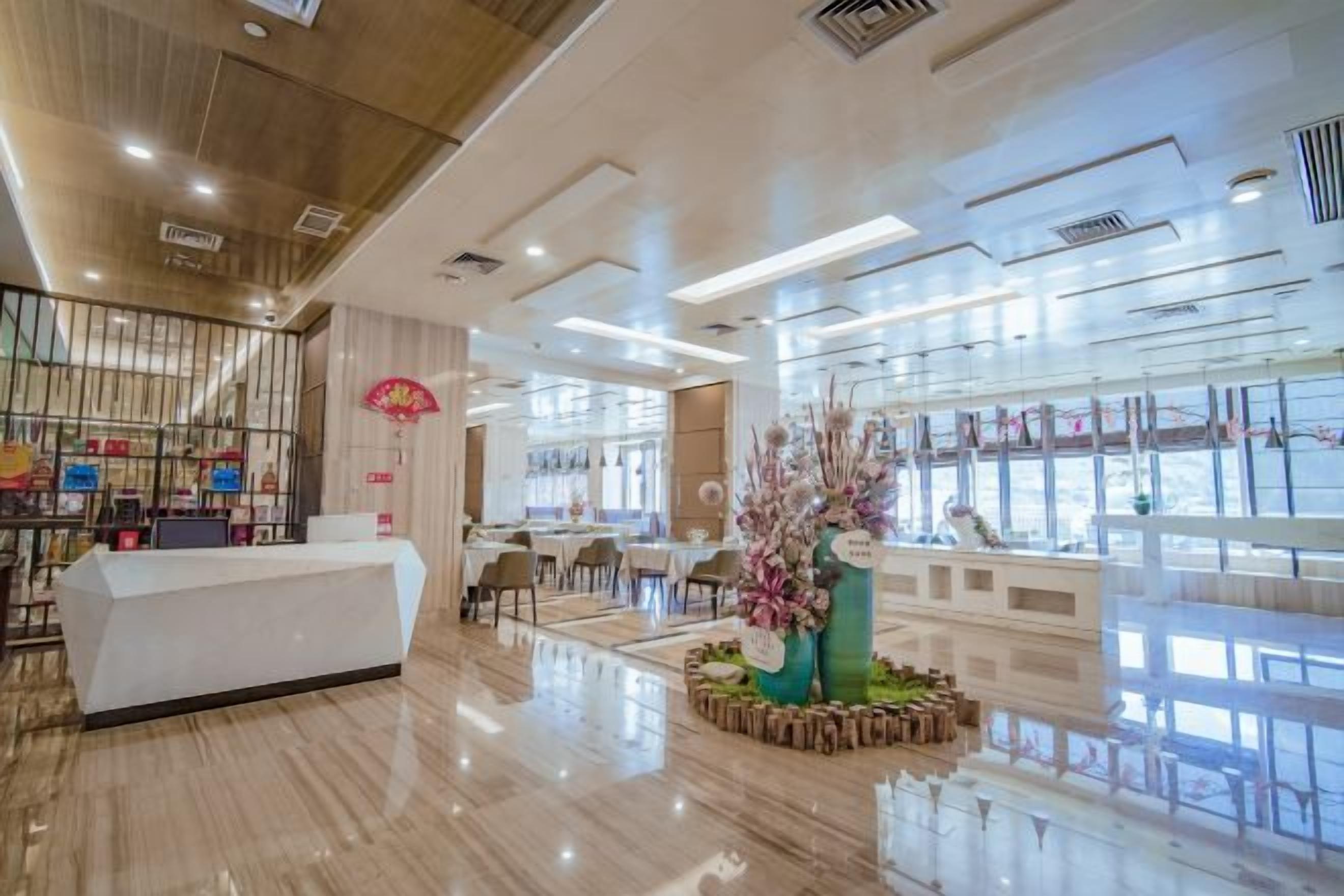 A hotel lobby with a reception desk, seating area, and large windows.