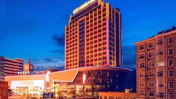 A high-rise hotel with a modern design, featuring a prominent clock tower in the background.