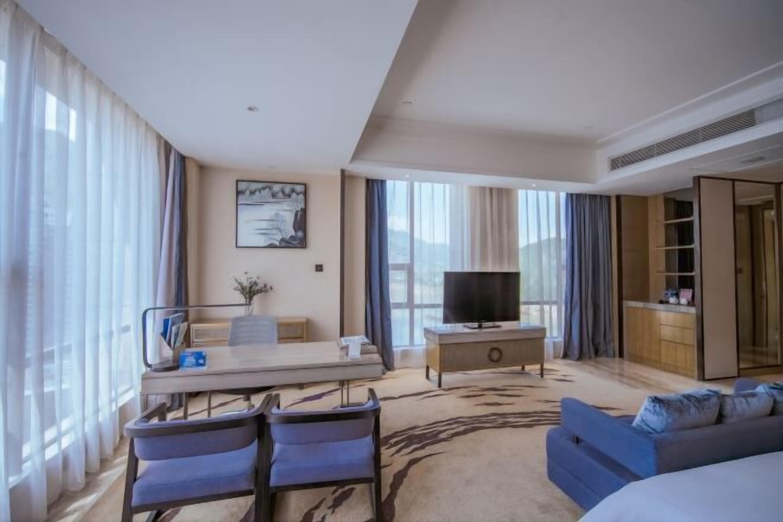 A hotel room with a bed, a desk, a TV, a sofa, and a wardrobe.