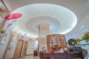 A hotel lobby with a high ceiling, a reception desk, and a decorative wooden partition.