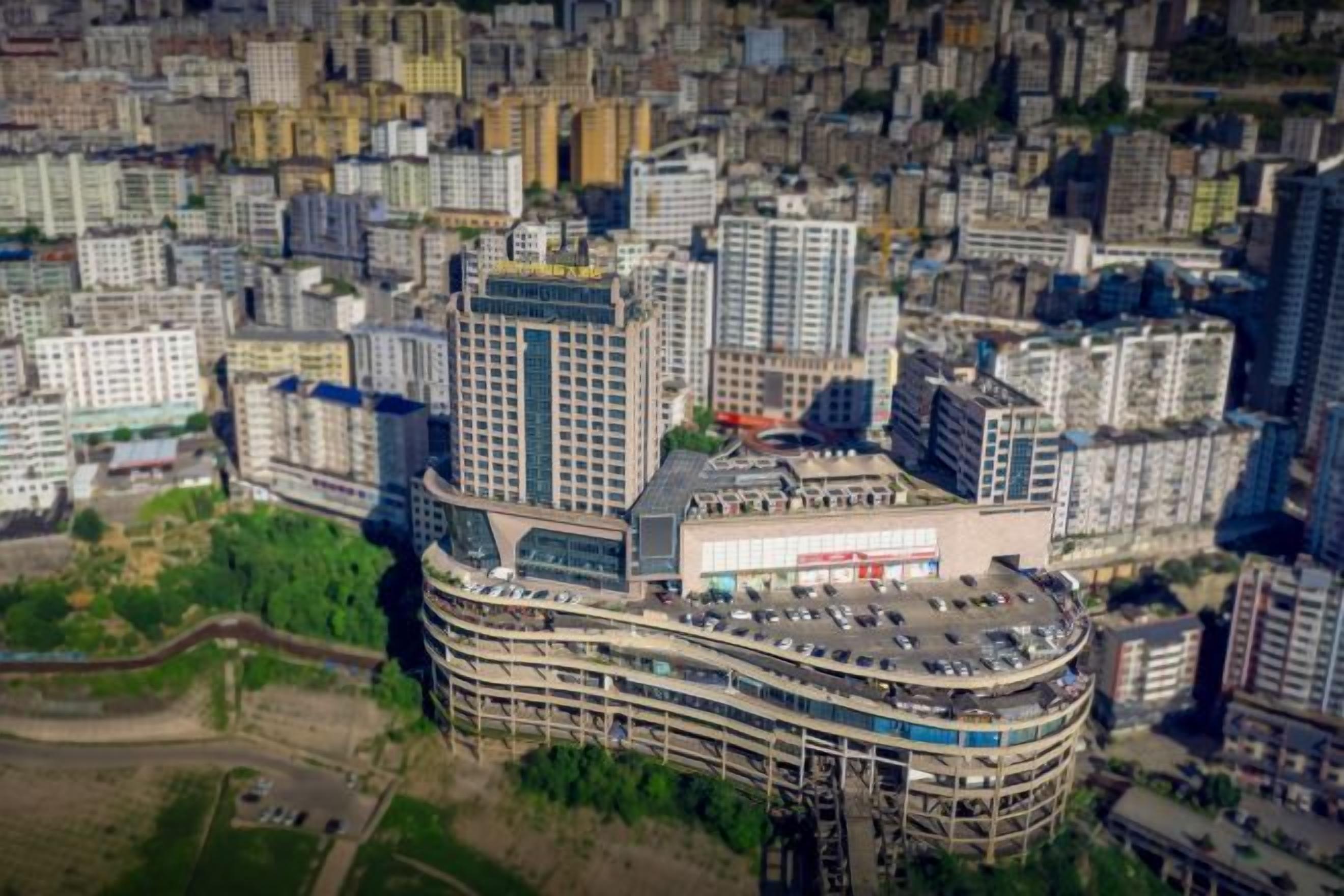 A multi-story building with a curved structure, surrounded by other buildings.