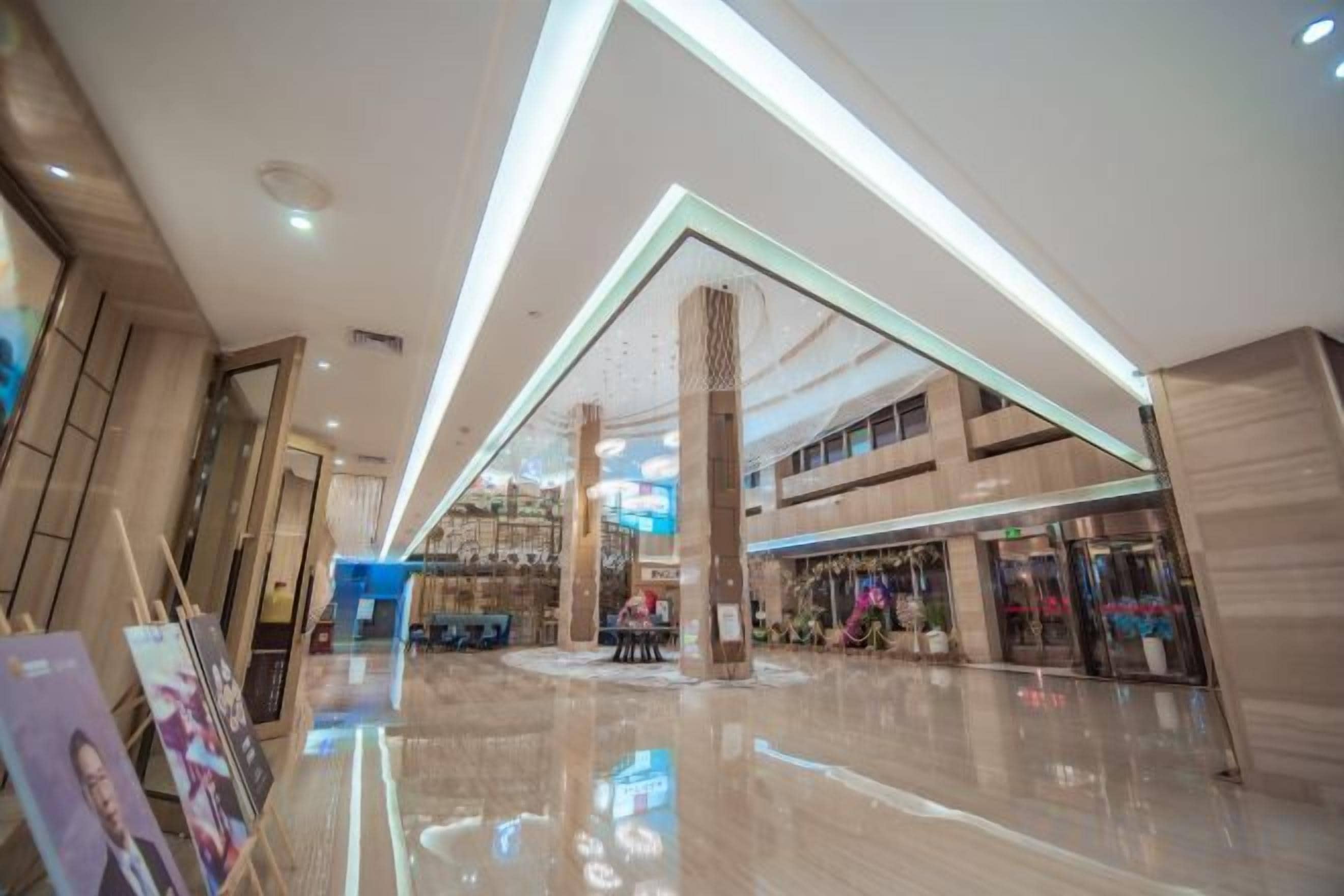 A spacious indoor area with a polished floor, a central column, and a ceiling with linear lighting.