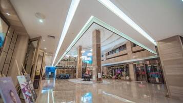 A spacious indoor area with a polished floor, a central column, and a ceiling with linear lighting.