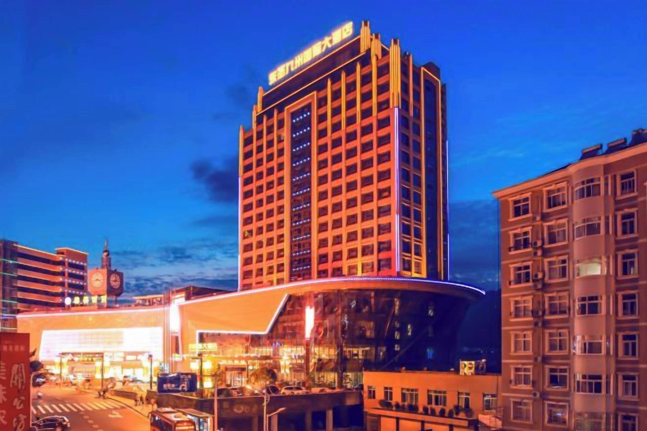 A multi-story hotel with a prominent corner building, large windows, and a well-lit facade.