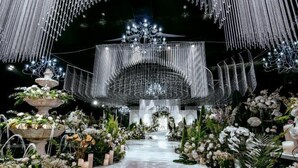Un espace intérieur doté d’une scène centrale, entourée de compositions florales et surmontée d’un lustre.