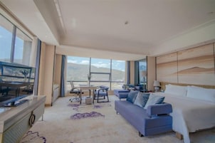 Una habitación de hotel moderna con una cama grande, un sofá, una mesa de comedor con sillas y un televisor.