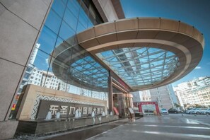 Un bâtiment moderne doté d’un toit en verre incurvé et d’une enseigne avec des caractères chinois.