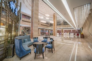 Een ruime lobby met een zithoek, een hoge plafond en een modern design.