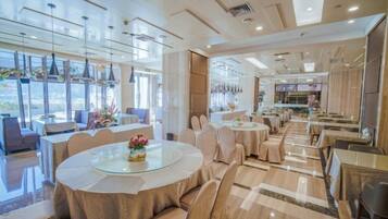 A spacious dining area with round tables and chairs, large windows, and a modern interior design.