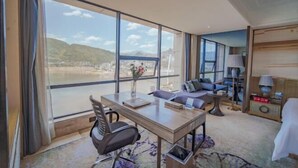 Une chambre d’hôtel avec une grande fenêtre, une table à manger, un canapé et une lampe.