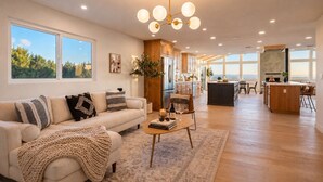 A spacious living area with a sofa, coffee table, and a view of the kitchen and dining area.