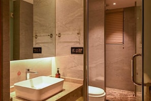 A modern bathroom with a rectangular sink, a toilet, and a glass-enclosed shower area. - Mingzhu Hotel (Qingchuan)