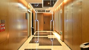 A modern hotel corridor with a polished floor, wooden walls, and a ceiling with recessed lighting. - Mingzhu Hotel (Qingchuan)