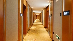A hotel hallway with a carpeted floor, wooden walls, and numbered doors. - Mingzhu Hotel (Qingchuan)