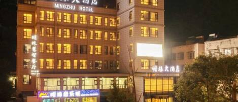 A multi-story hotel with illuminated signage and a parking lot.