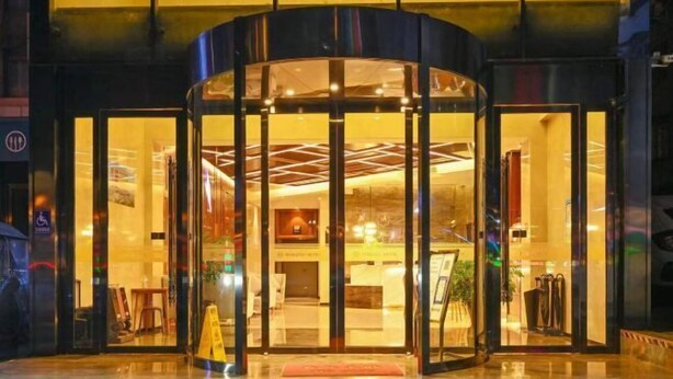A hotel entrance with a revolving door, glass doors, and a reception desk visible inside. - Mingzhu Hotel (Qingchuan)