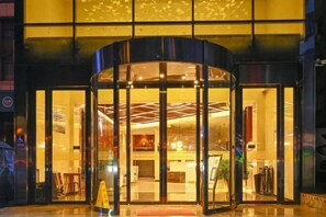 A hotel entrance with a revolving door, glass doors, and a reception desk visible inside. - Mingzhu Hotel (Qingchuan)