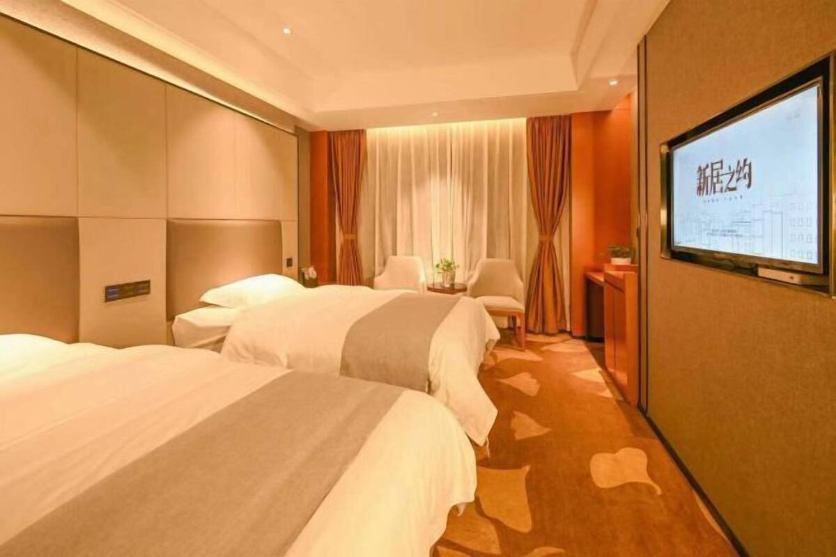 A hotel room with two beds, a television, and a large window with curtains.