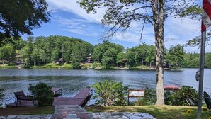 Una passeggiata lungo il lago con un molo di legno, panchine e una zona con pavimento in pietra.
