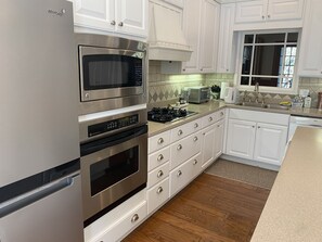 A modern kitchen with white cabinets, stainless steel appliances, a built-in microwave, and a gas stove.