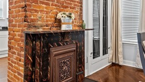 A brick fireplace with a decorative mantel, a wooden door, and a rug on the floor.