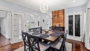A dining area with a wooden table, black chairs, and a chandelier.