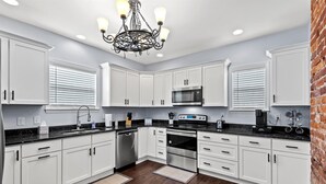 A modern kitchen with white cabinets, a stainless steel range, and a black countertop.