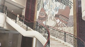 A grand staircase with ornate railings and a large mural depicting traditional figures. - Lian Shan Longshan Garden Hotel (Lianshan)
