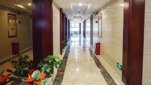 A hotel corridor with a marble floor, wooden paneling, and potted plants. - Lian Shan Longshan Garden Hotel (Lianshan)