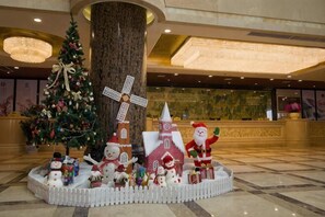 A Christmas display with a decorated tree, a windmill, and Santa Claus in a hotel lobby. - Lian Shan Longshan Garden Hotel (Lianshan)