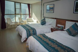 A hotel room with two beds, a small table, chairs, and a large window. - Lian Shan Longshan Garden Hotel (Lianshan)