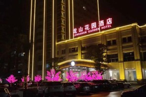 A hotel with a prominent sign, a parking lot, and illuminated trees. - Lian Shan Longshan Garden Hotel (Lianshan)