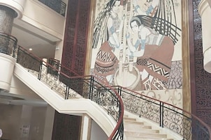 Un interior de varios niveles con barandillas ornamentales y un mural grande.
