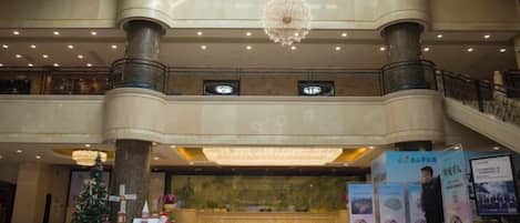 A spacious lobby with a grand staircase, multiple levels, and a Christmas tree decoration.
