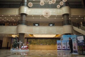 A spacious lobby with a grand staircase, multiple levels, and a Christmas tree decoration. - Lian Shan Longshan Garden Hotel (Lianshan)